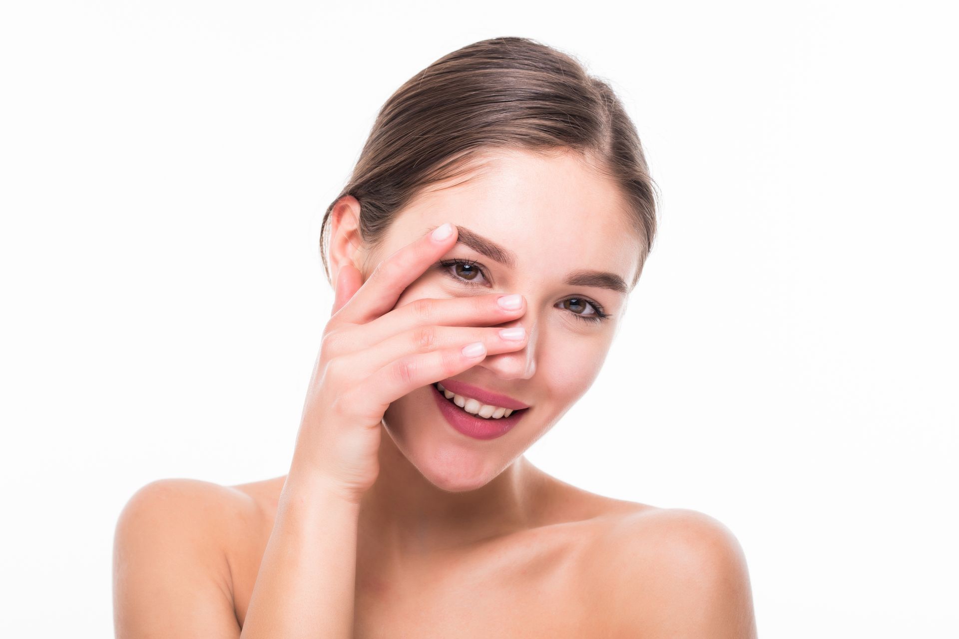 A woman is covering her face with her hand and smiling after neurotoxin treatment.