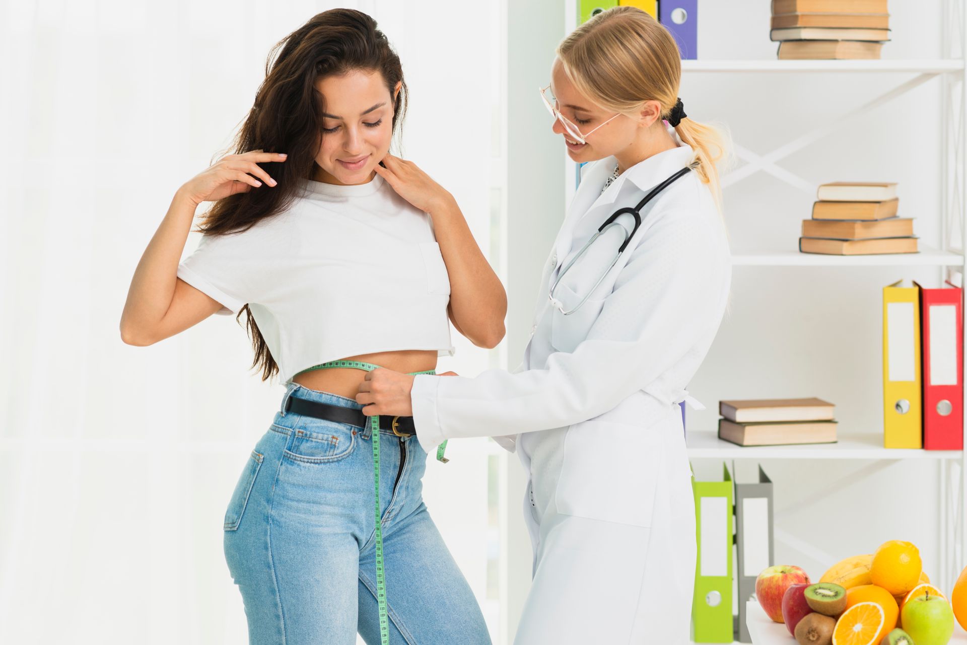 A doctor is measuring a woman 's waist with a tape measure.
