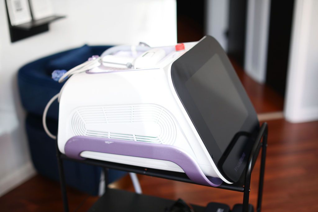 A white and purple machine is sitting on a cart in a room.