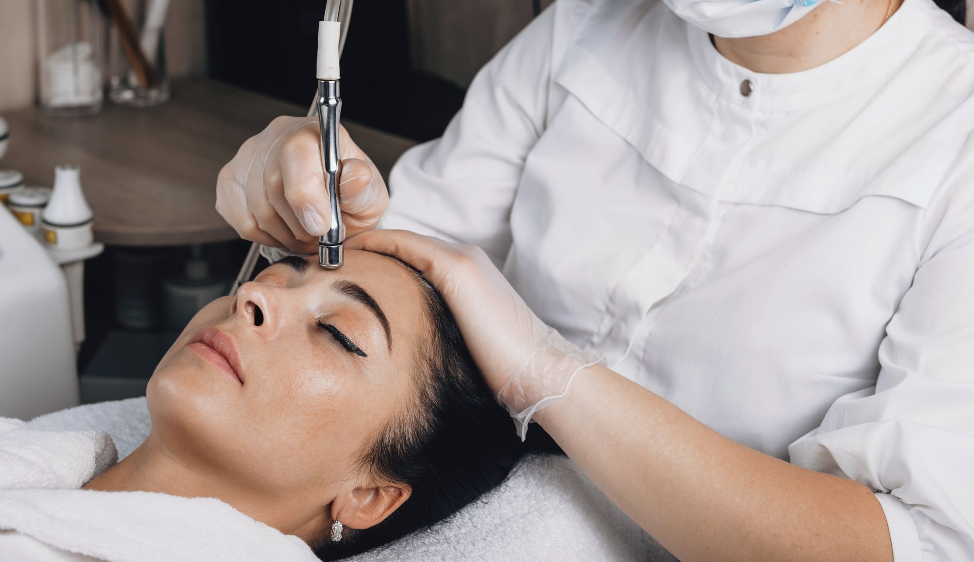 Cosmetic treatment with a handheld device on a woman’s forehead in a clinic