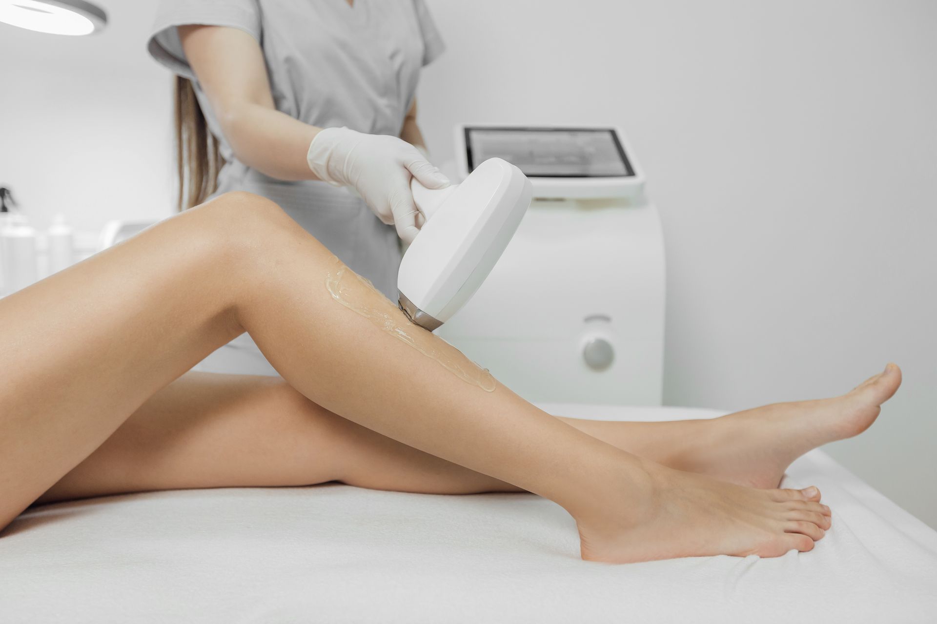 Laser hair removal on a person's leg at a medical spa; a technician operates the device.