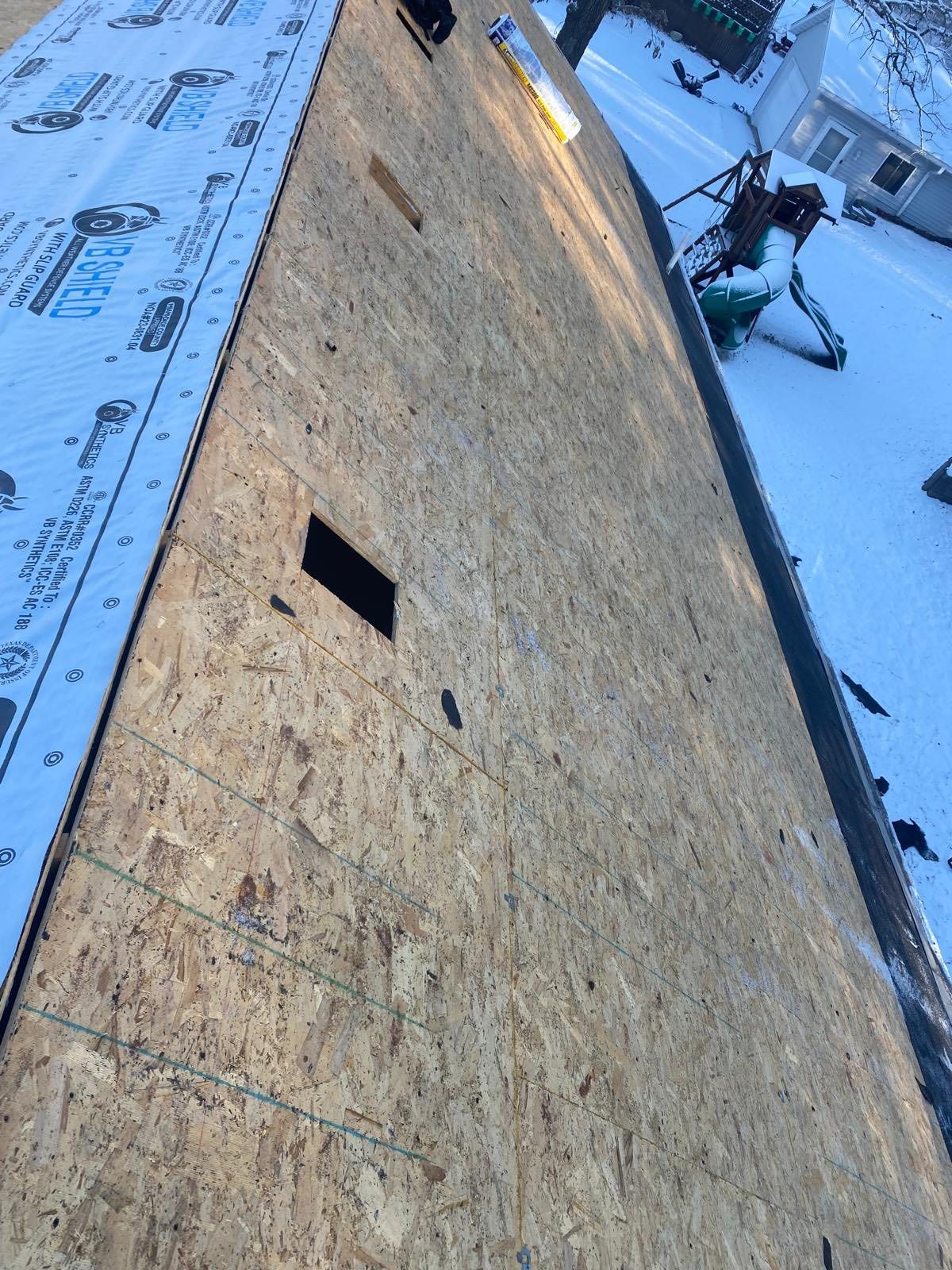 Rooftop underlayment with a rectangular opening and snowy ground along the edge