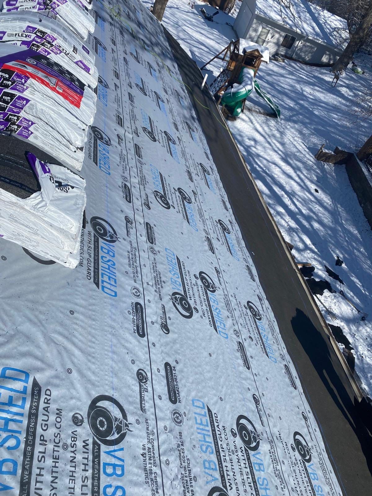 Snow-covered roof under construction with workers and tools in a winter scene