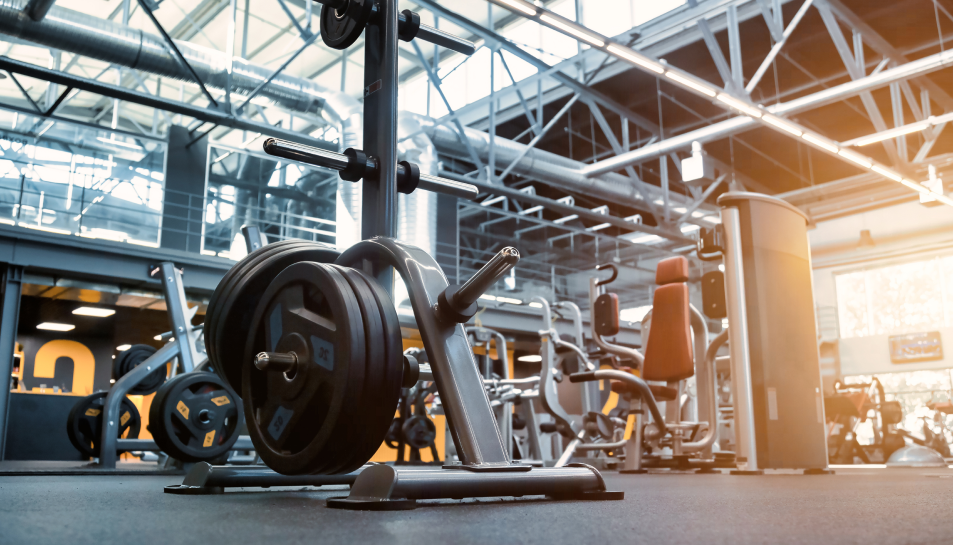 Gym interior with weight machines and a barbell loaded with weights.
