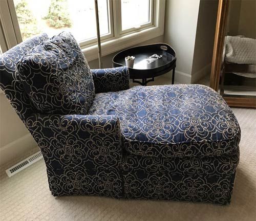 A blue chair and ottoman are in a room next to a window.