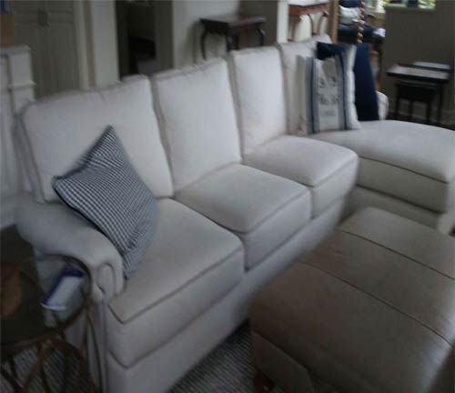 A living room with a white couch and ottoman
