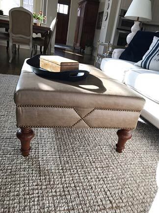 An ottoman is sitting on top of a rug in a living room next to a couch.