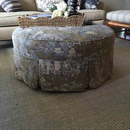 A round ottoman is sitting on top of a coffee table in a living room.