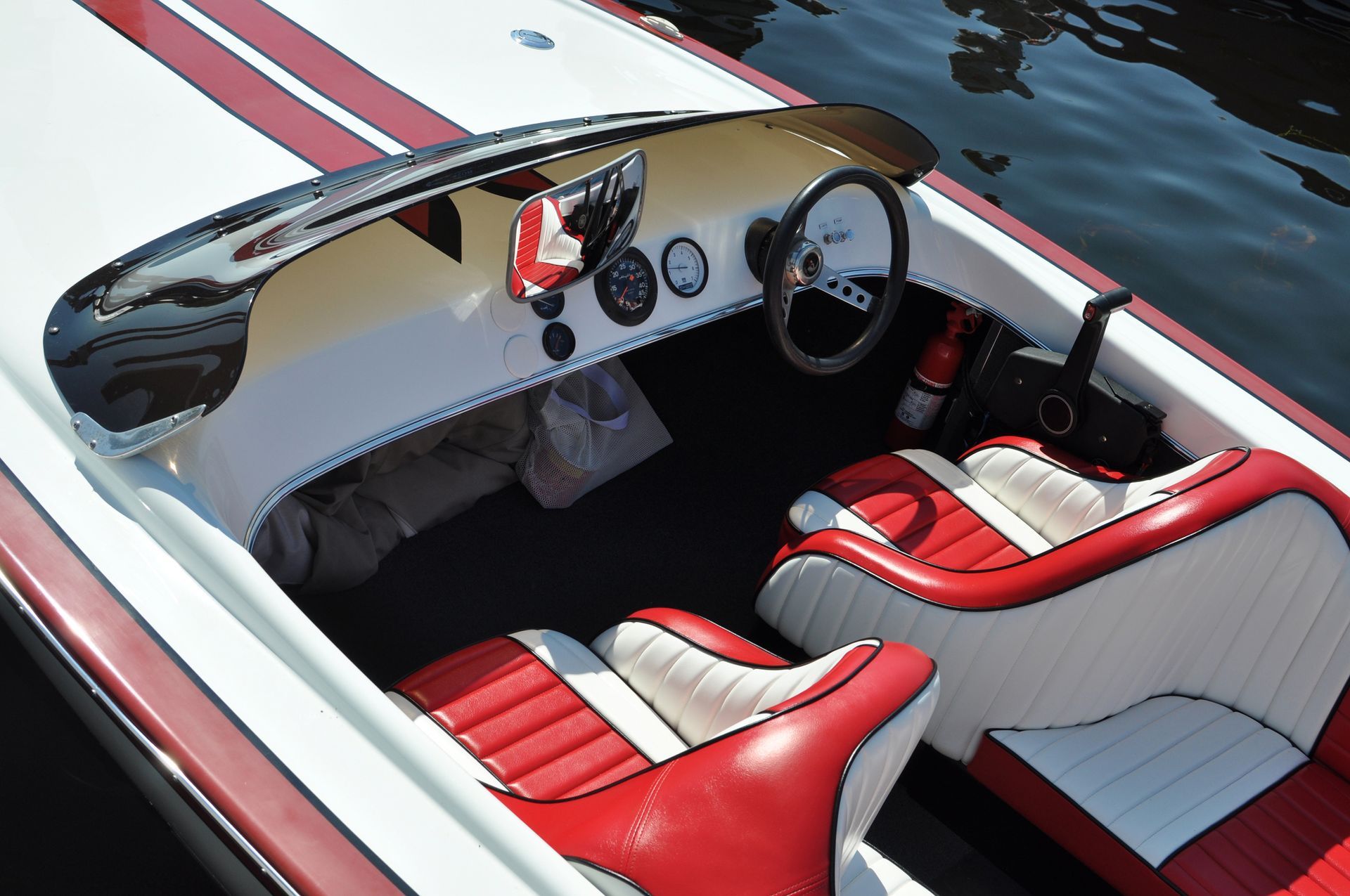 A boat with red and white seats and a steering wheel