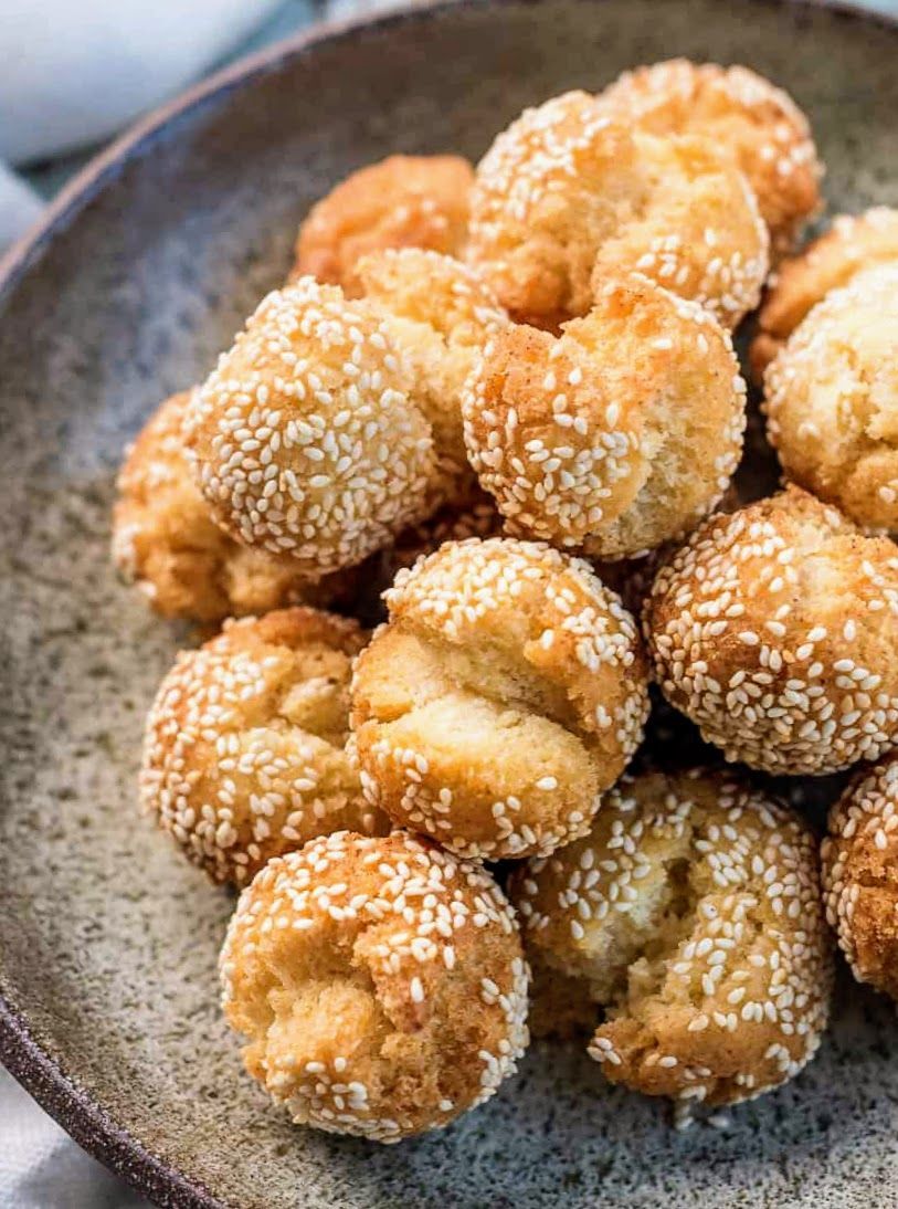 Plate of sesame-coated golden fried pastries stacked in a bowl