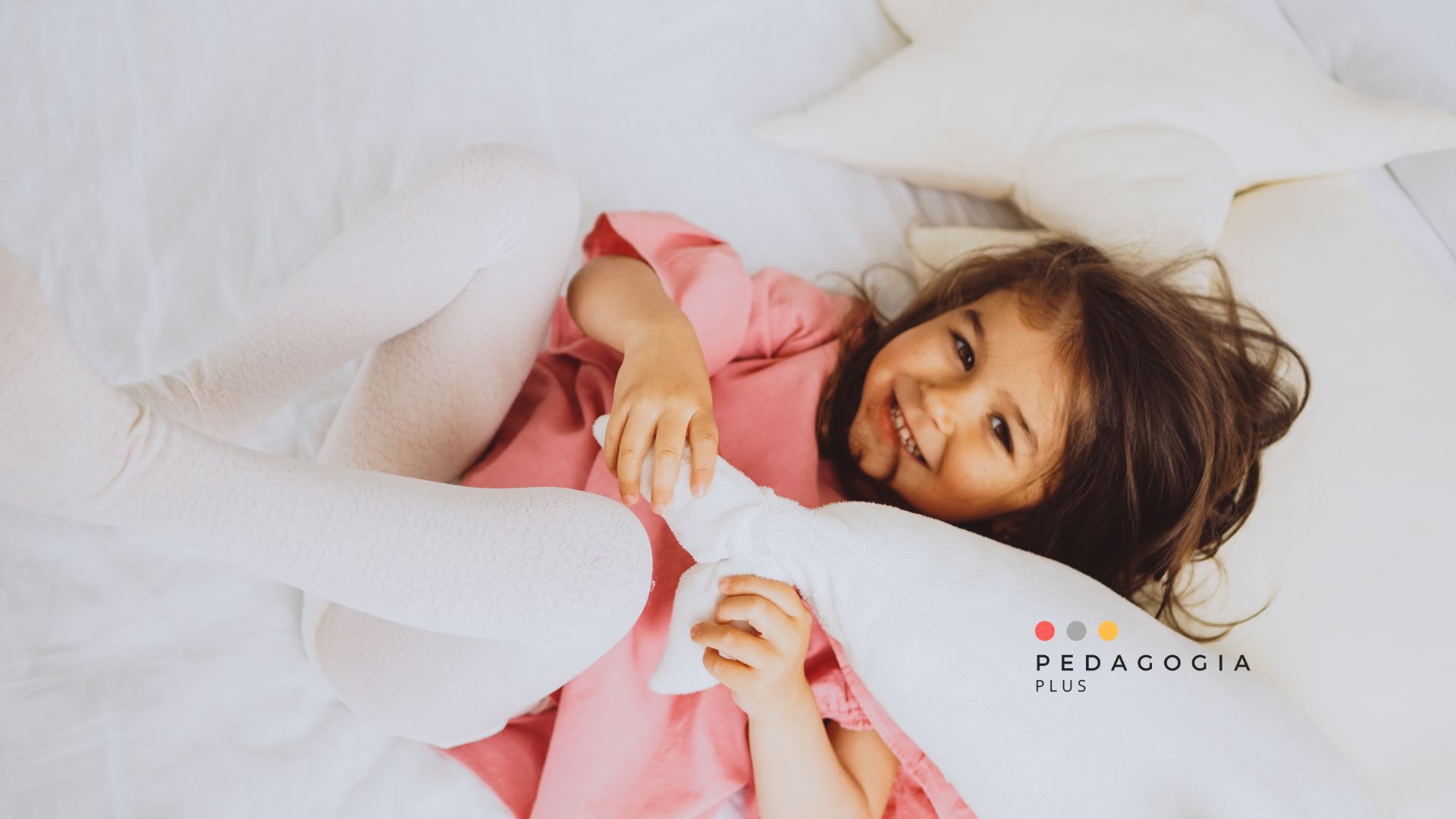 Bambina sul letto che gioca con i cuscini invece di dormire