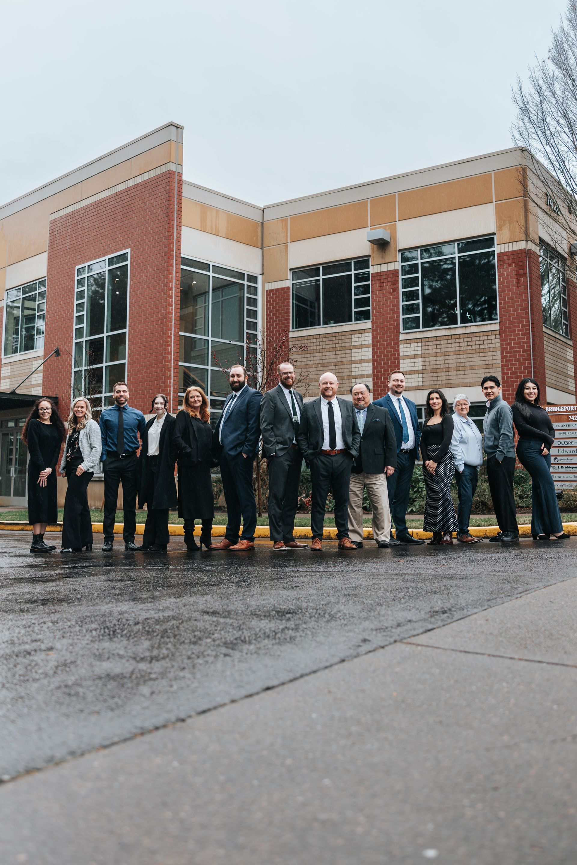 Group of people in formal attire standing in front of a brick building.
