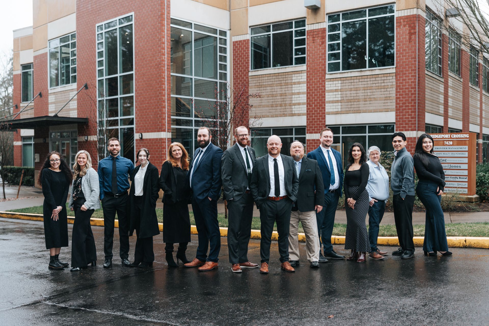 Group of people posing in a modern office setting in front of large windows.