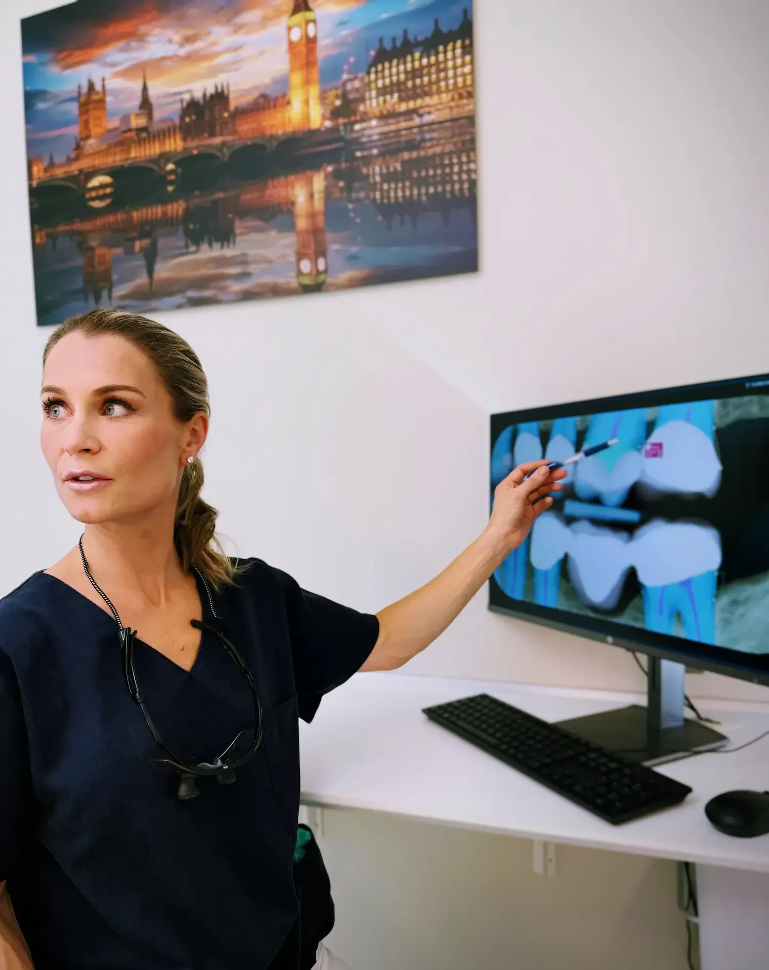 Tannlege peker på røntgenbilde på skjerm på kontor med kunst av Londons skyline.