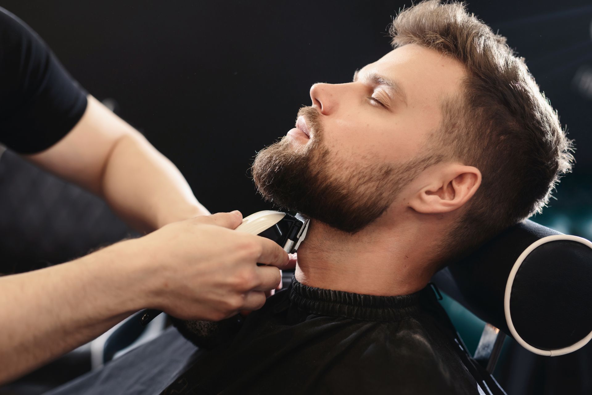 A man is getting his beard shaved by a barber.