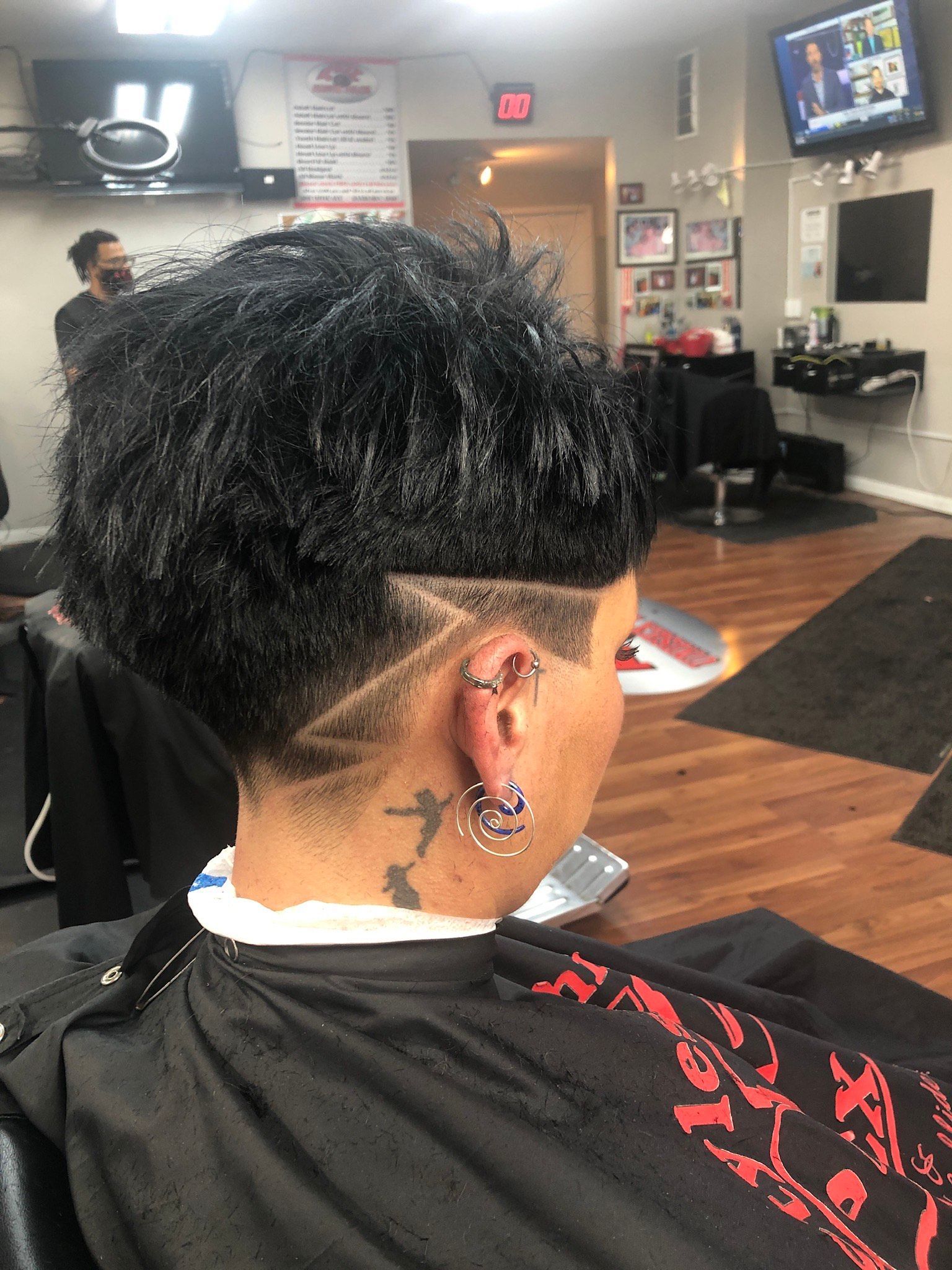 A woman is getting her hair cut at a barber shop.