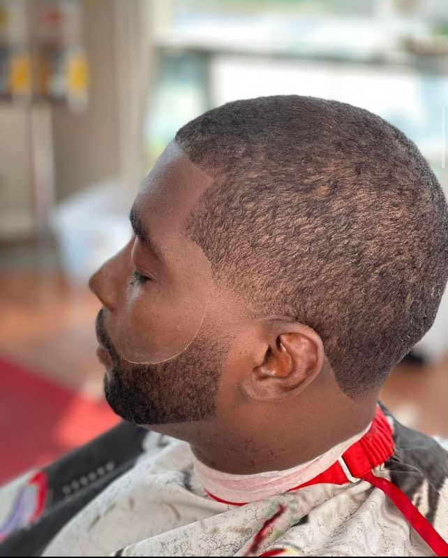A man with a beard is getting his hair cut at a barber shop.