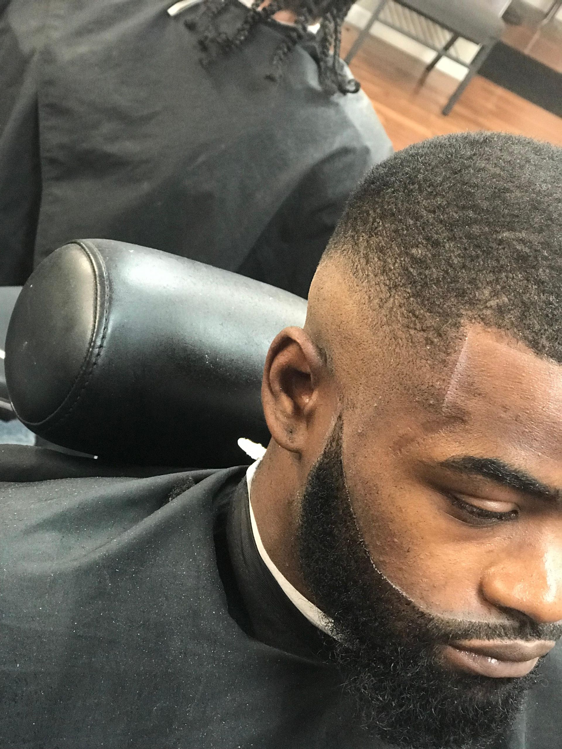 A man with a beard is getting his hair cut at a barber shop.