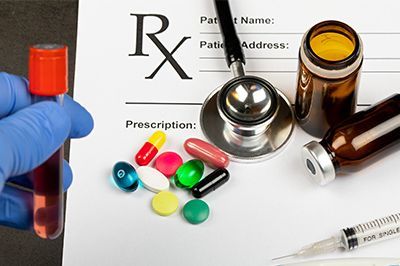 A person is holding a test tube next to a prescription and a stethoscope.