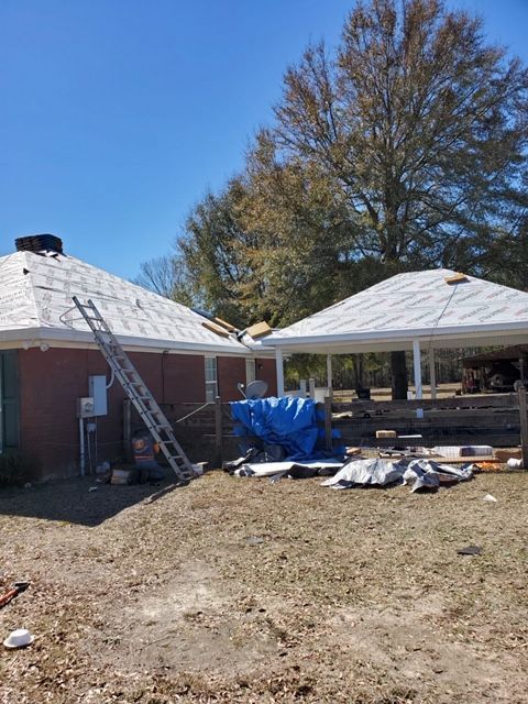 A house roof being repaired with a ladder and tarp on the ground; sunny day.
