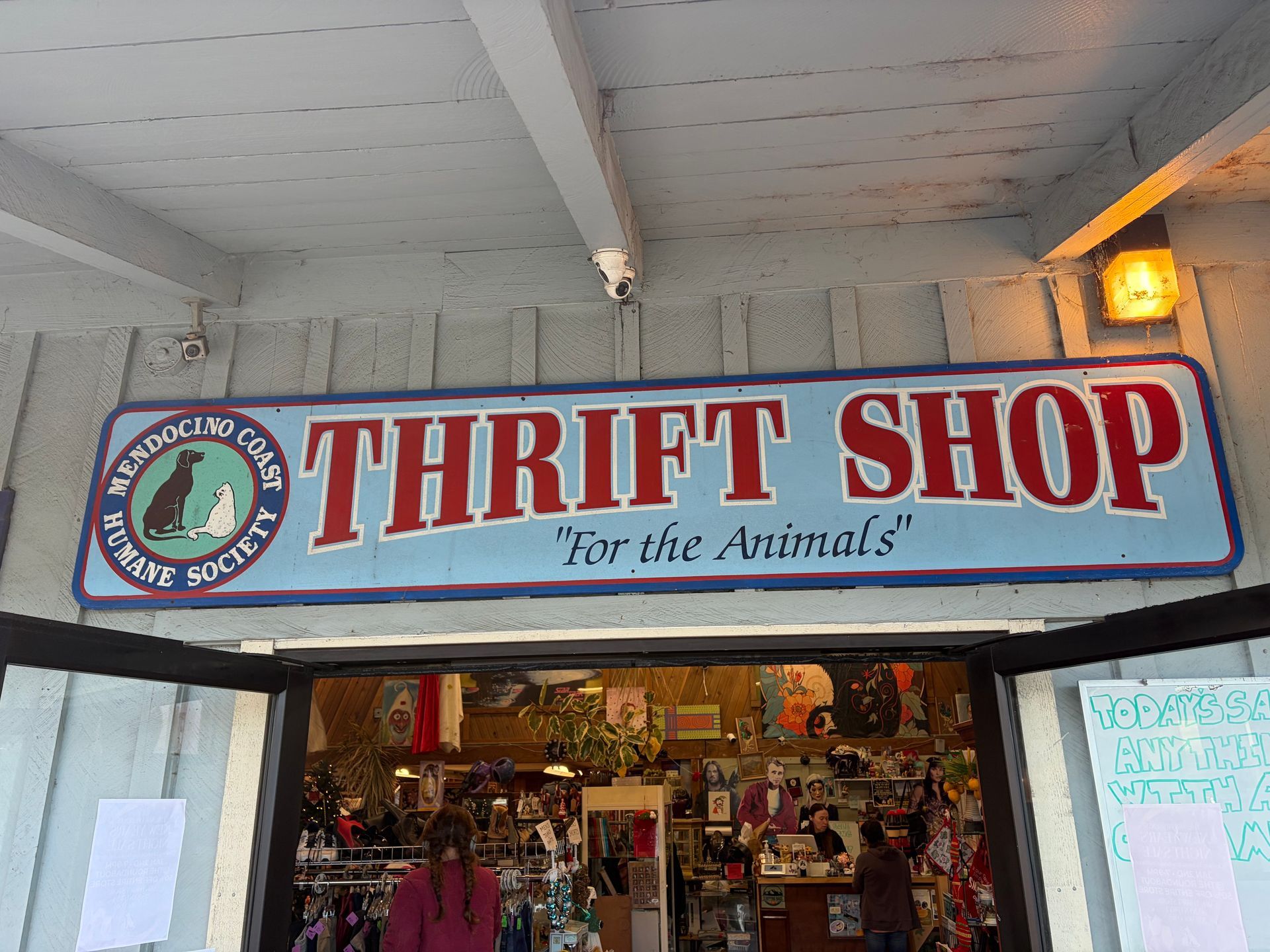 Sign for a thrift shop run by a humane society, above an open doorway.