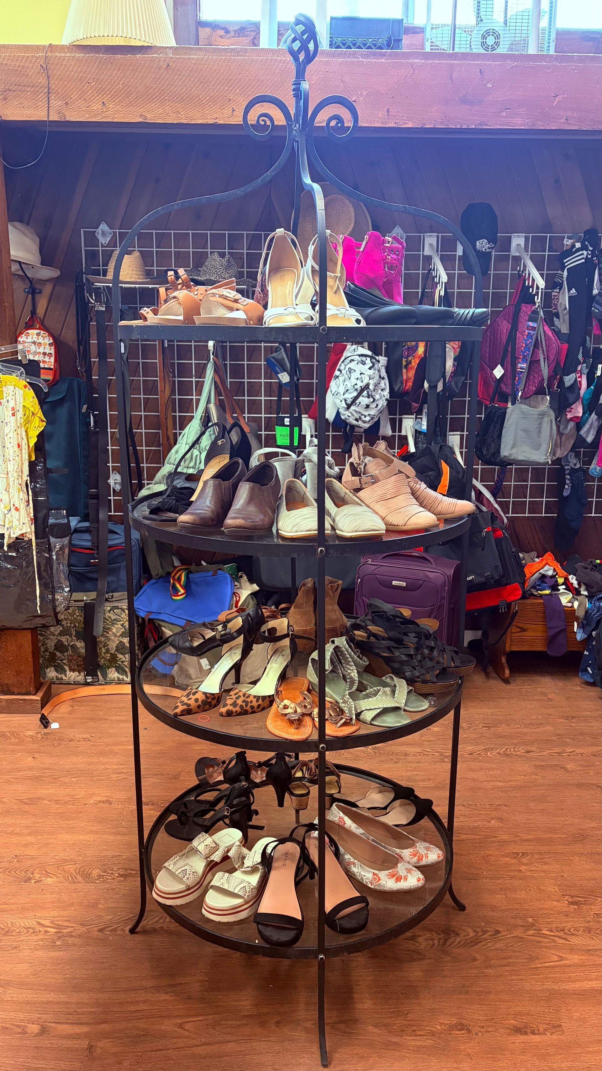 Round metal shoe display with various sandals and shoes in a store.