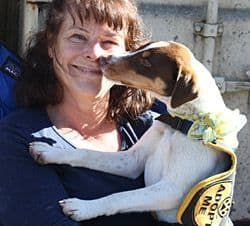 Woman holding a small dog wearing an 