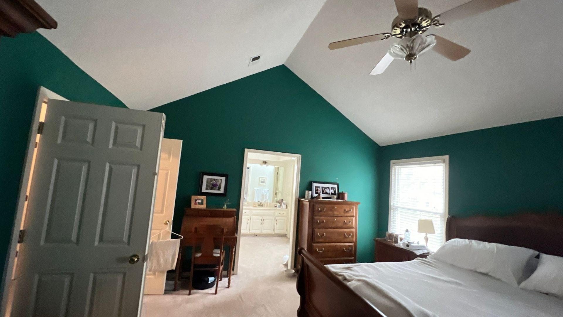 Spacious, empty room with dark wood-look flooring. Large windows and a curved staircase are visible.