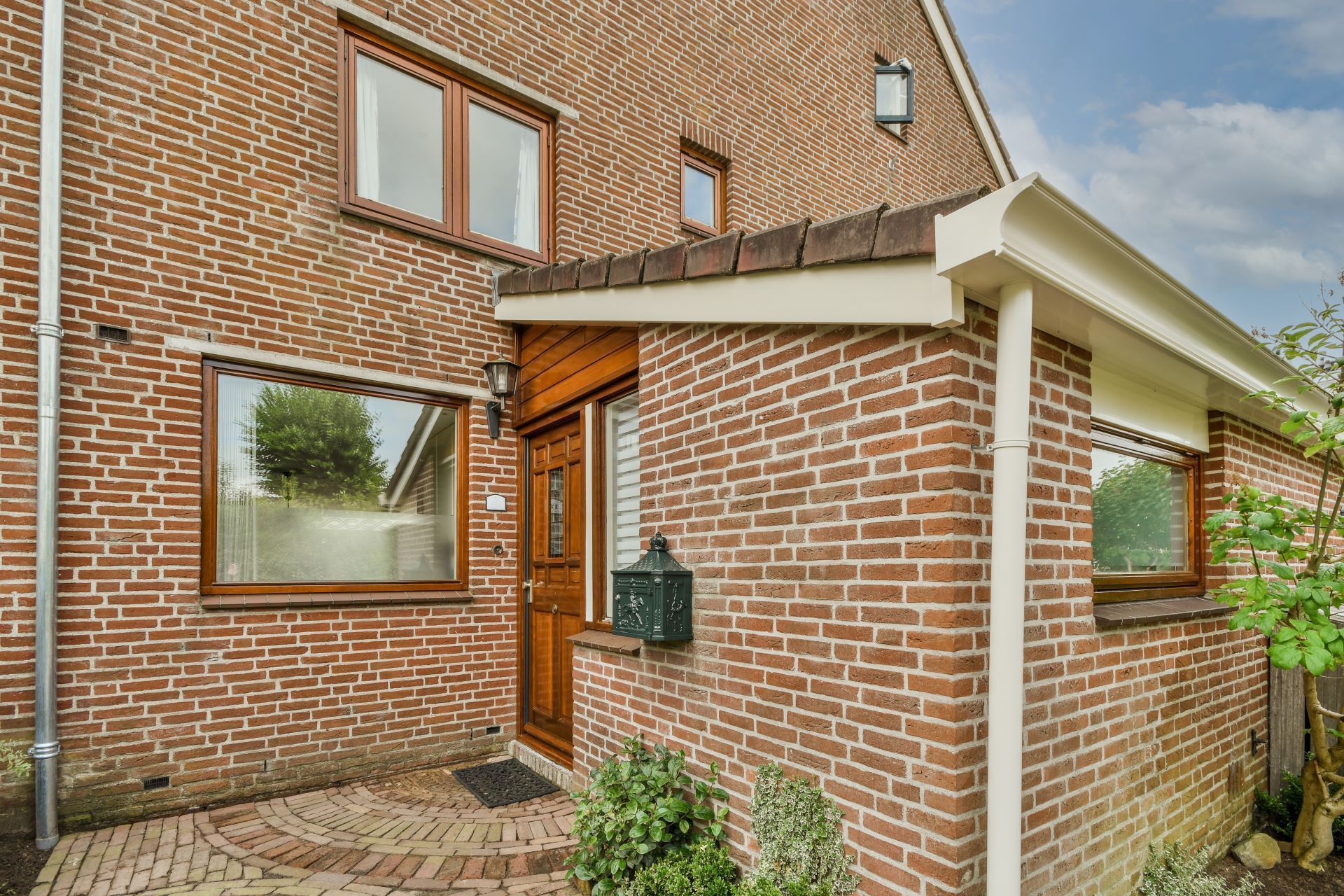 Brick house with brown windows, door, and a small porch.