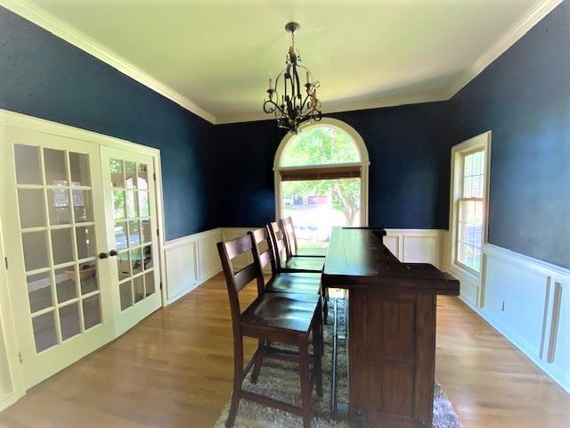 Room with dark blue walls, white trim, wood bar, and chairs, with French doors and an arched window.