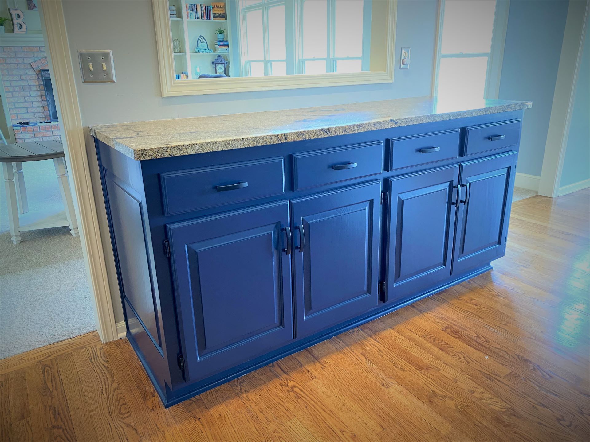 Dark blue cabinet with granite countertop, set against a wall. Wooden floor.