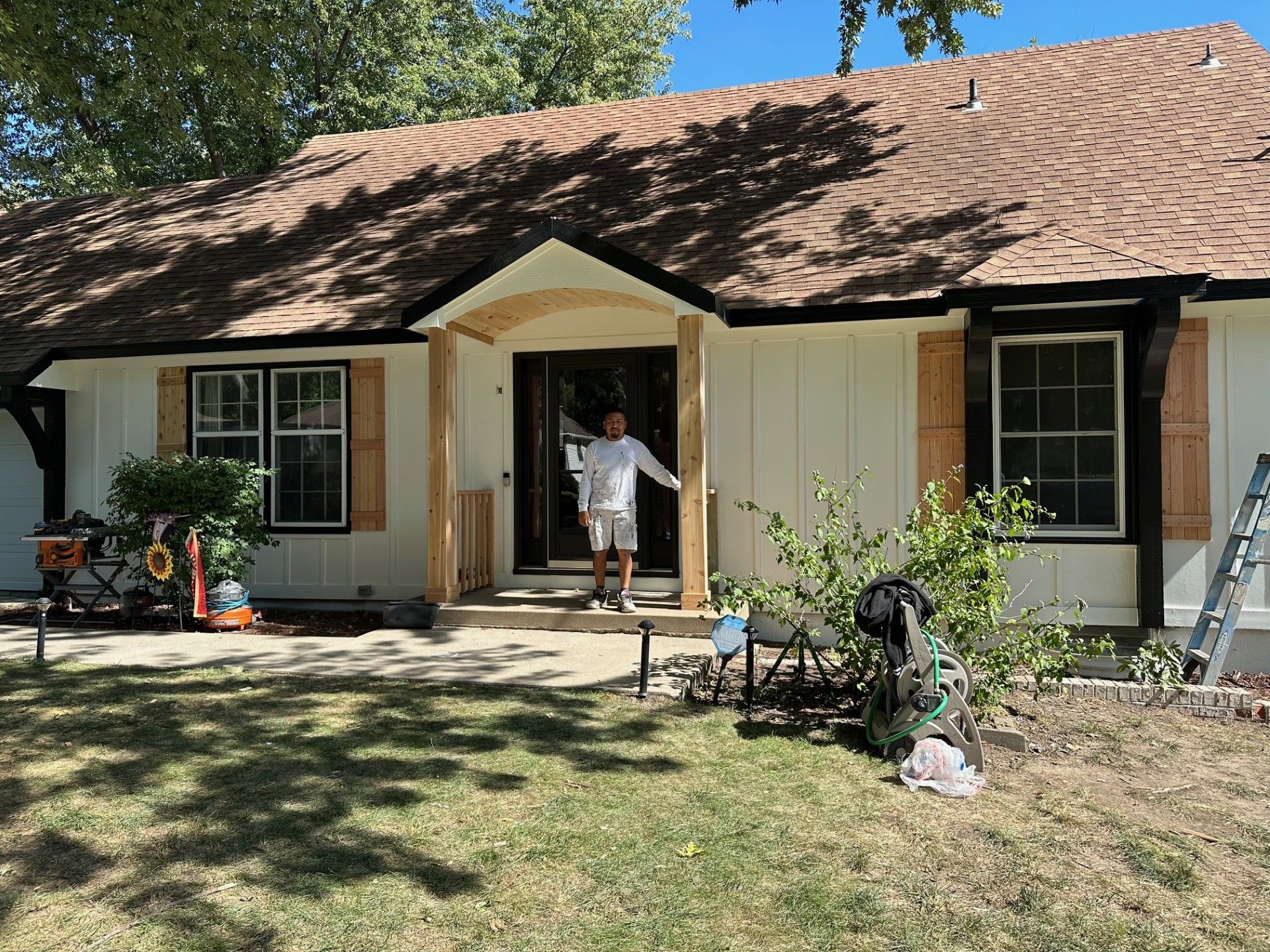 White house with dark trim, sealed wood, and a light brown roof
