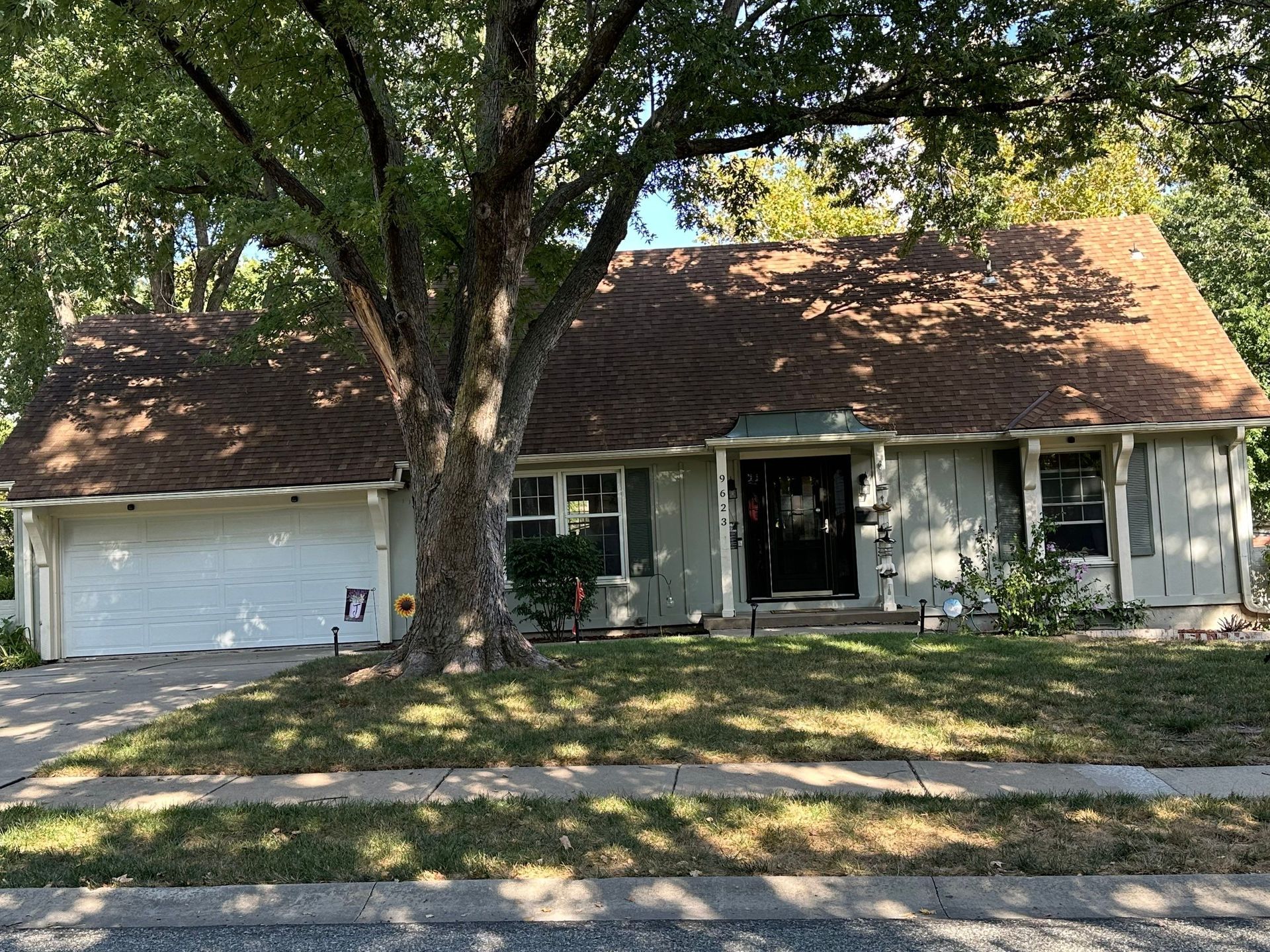 Ranch style house with neutral colors and white trim. Light brown roof, and white garage door