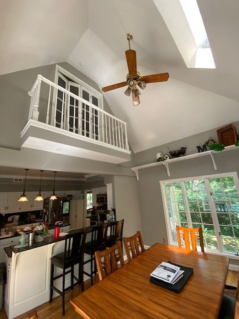 Kitchen and dining area with a loft. Gray walls, wooden table and chairs, and white railing.