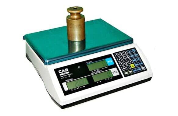 Una báscula digital con un peso de latón encima.