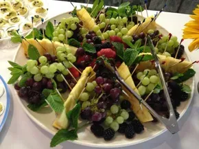 A plate of fruit with tongs on a table.