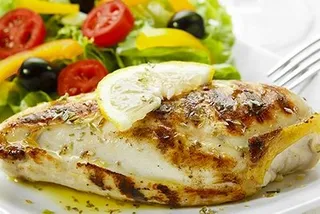 A white plate topped with chicken and a salad with a fork.