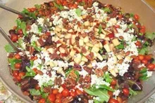 A close up of a salad in a bowl with a spoon in it.