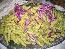 A close up of a plate of pasta salad with purple cabbage on a table.