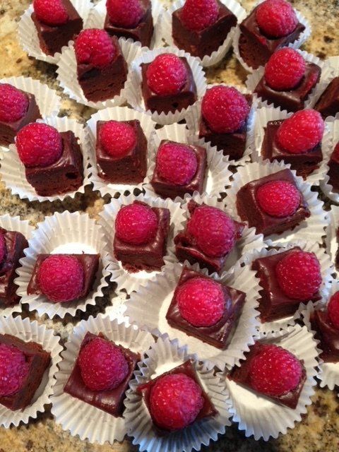 A bunch of chocolate squares with raspberries on top