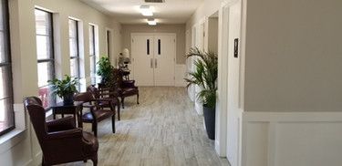 A long hallway with chairs and plants in a building.