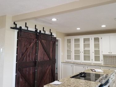 A kitchen with a sliding barn door and white cabinets.