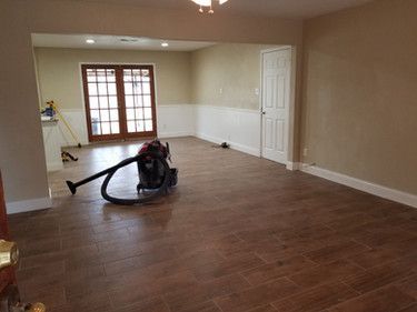 A vacuum cleaner is sitting on a wooden floor in an empty room.