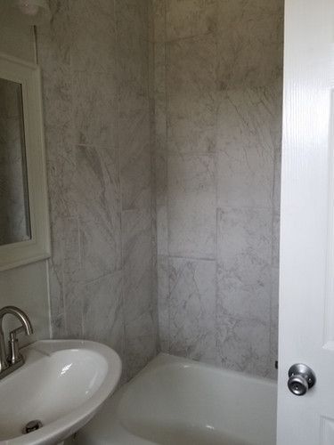 A bathroom with a sink , tub and mirror.