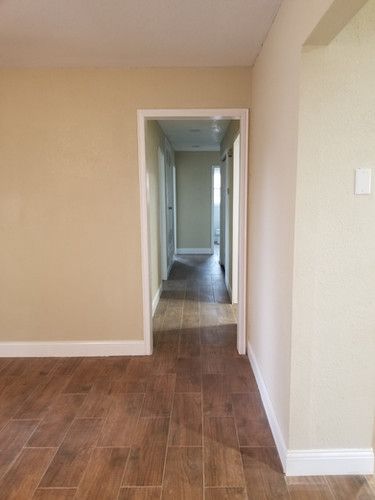 A hallway in a house with wooden floors and beige walls.