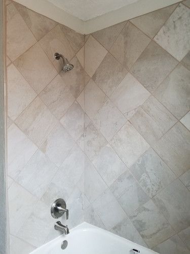 A bathroom with a bathtub , shower , and tiled walls.