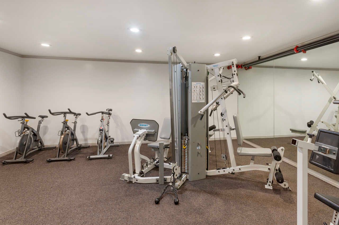 A gym with a lot of exercise equipment and a large mirror.