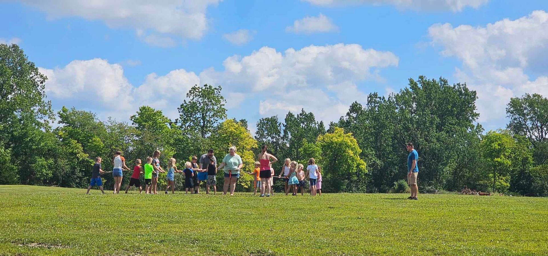 a group of people are standing in a circle in a grassy field