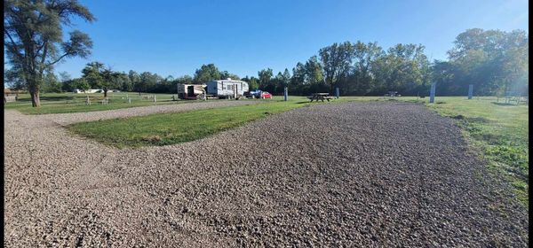 a rv is parked in a gravel lot with picnic tables