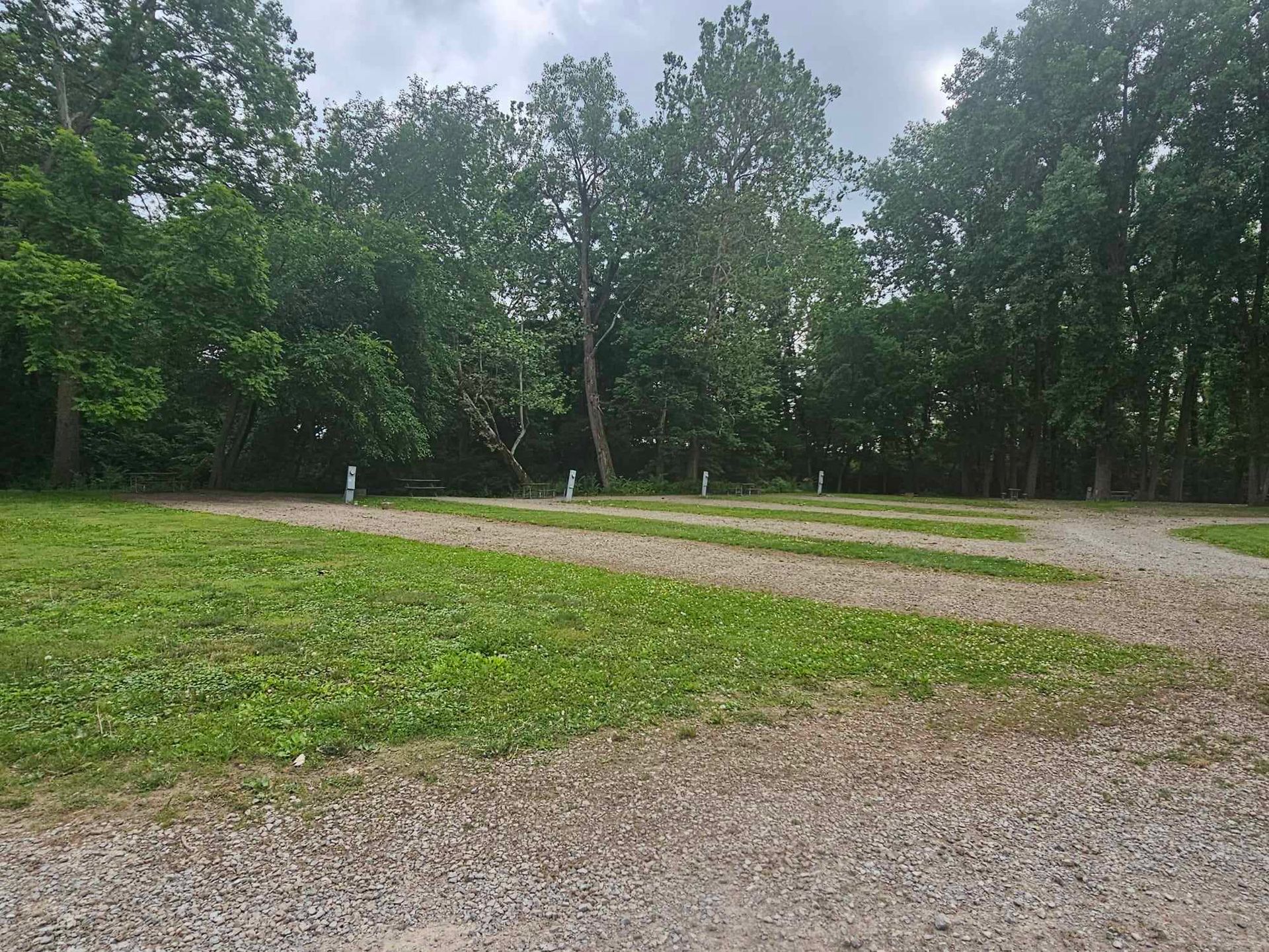 a gravel road going through a park with trees in the background